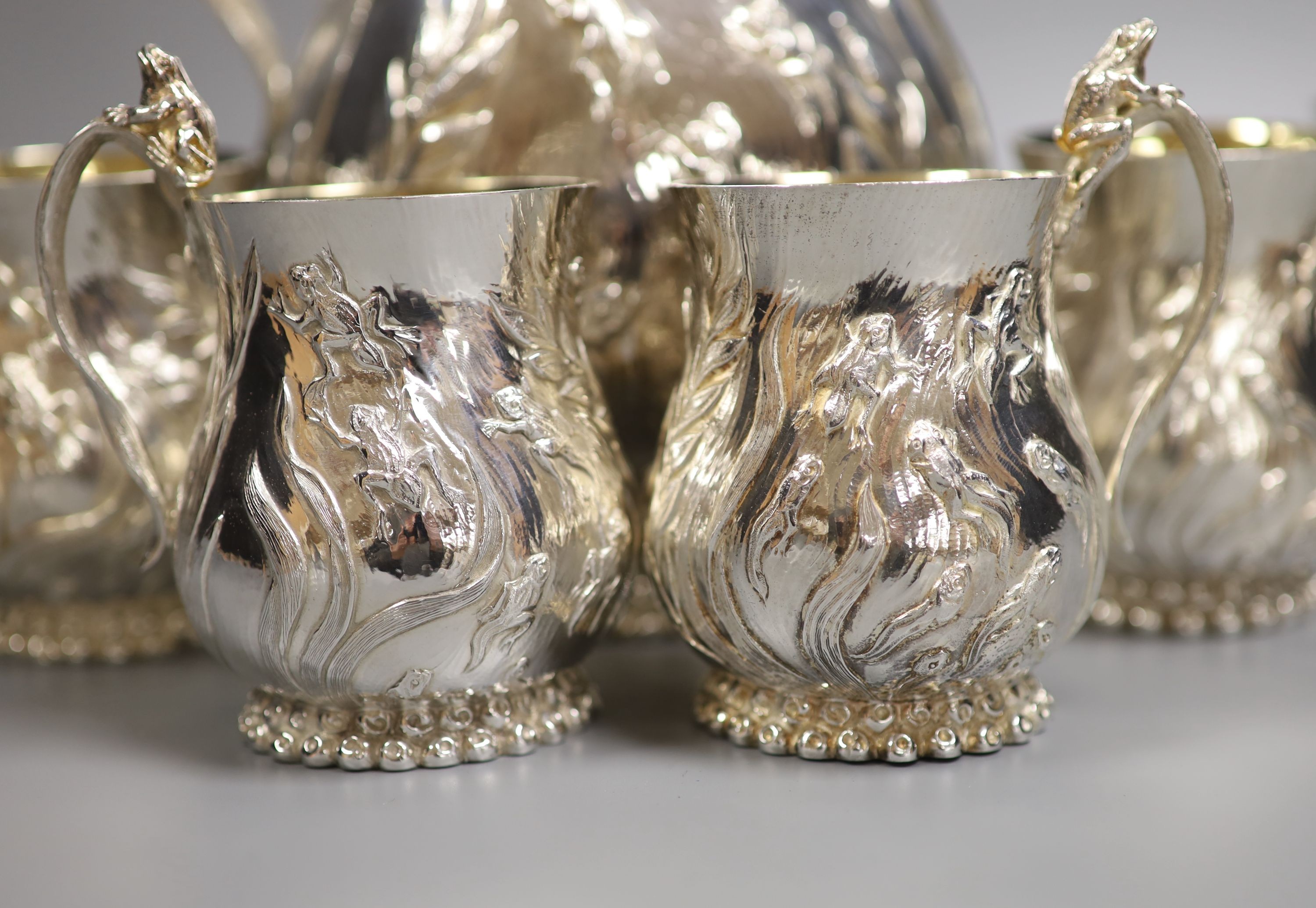 A good set of six Garrard & Co Ltd silver mugs and a matching jug, London, 1997, all embossed with frogs spawn amongst reeds, with gilded interiors, jug height 27.1cm